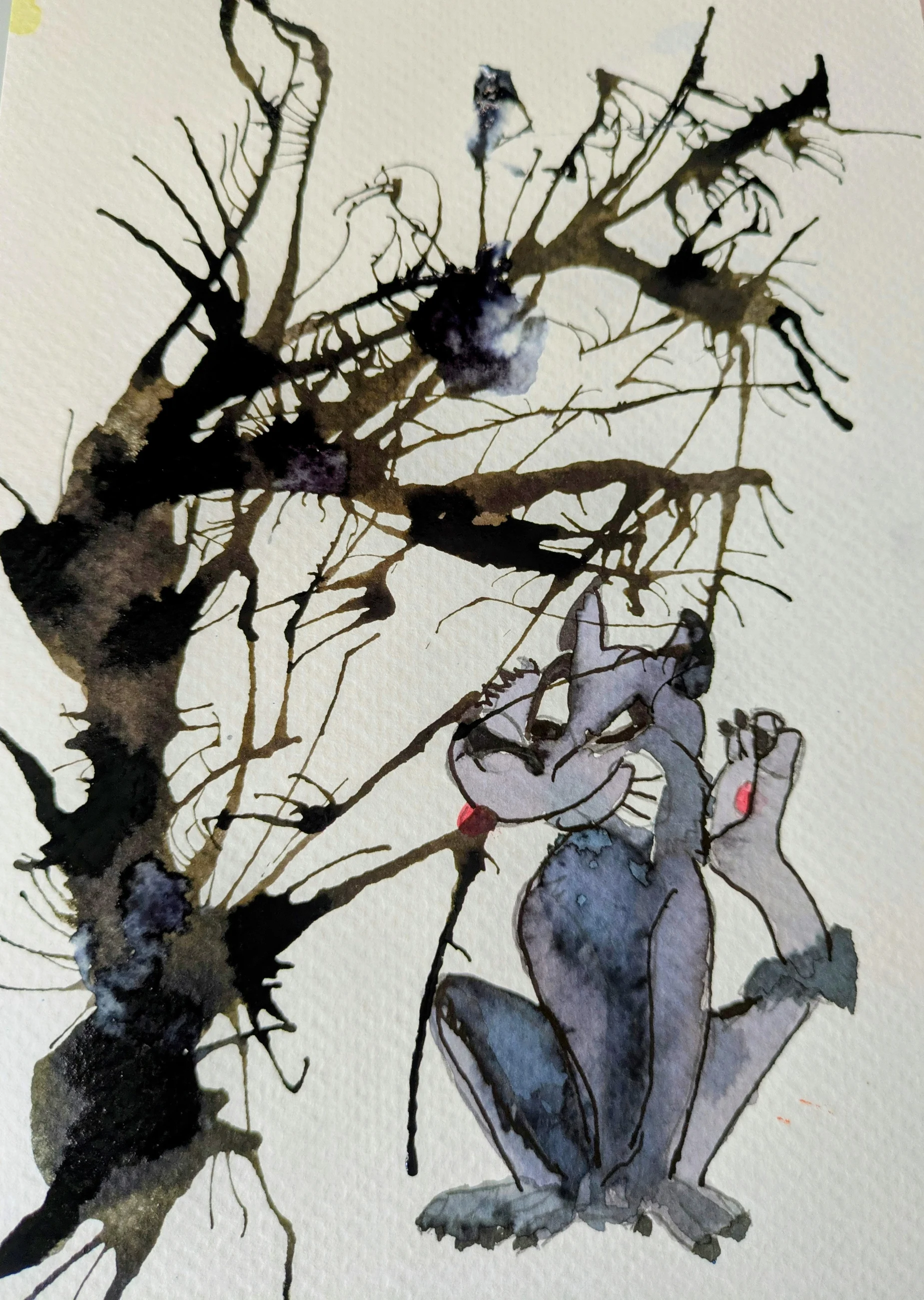 Un chat gris se tient au pied d’un réseau de branches noires.